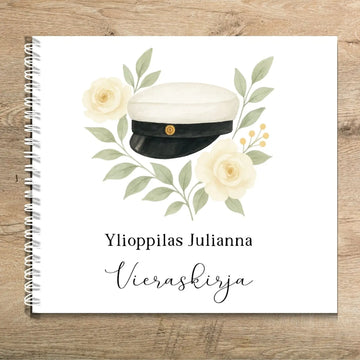 Vieraskirja ylioppilasjuhliin ylioppilaslakki ja keltaisia kukkia Decopaja