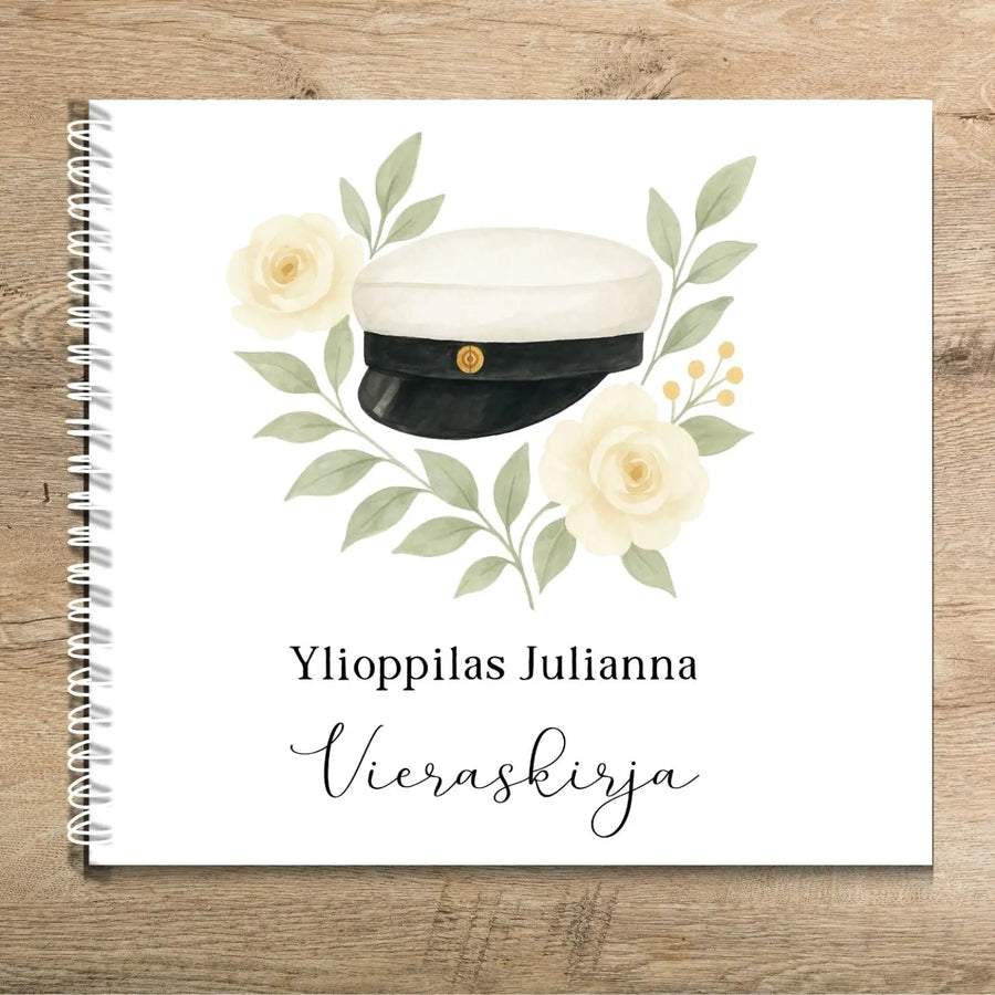 Vieraskirja ylioppilasjuhliin ylioppilaslakki ja keltaisia kukkia Decopaja